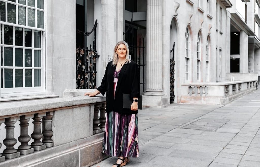 Business consultant and keynote speaker standing outside a historic building, prepared for a professional speaking engagement.