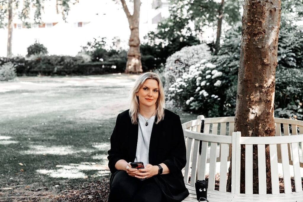 Business consultant sitting on a bench in a park with a phone in hand, representing strategic consulting and leadership services