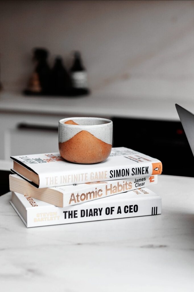 Stack of business strategy books with coffee cup symbolising productivity and focus for the Brew and Do Club